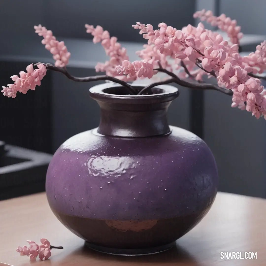 A purple vase filled with pink flowers sits gracefully on a table in a room with black walls. The soft, vibrant colors of the flowers contrast beautifully with the deep tones of the room.