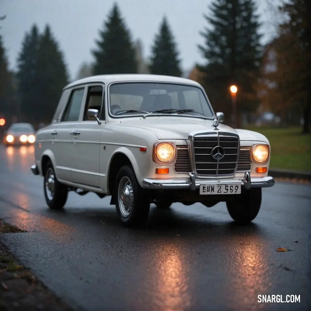 A pristine white Mercedes-Benz gleams under the sunlight, showcasing its sleek lines and sophisticated design. This automotive beauty embodies luxury and elegance, captivating onlookers with its stunning presence and undeniable charm on the open road.