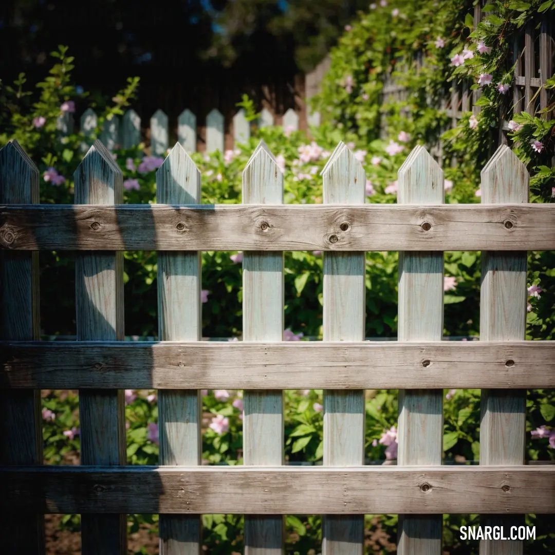 Wooden fence with a flower garden behind it and a fence with a wooden fence. Example of Olive Drab color.