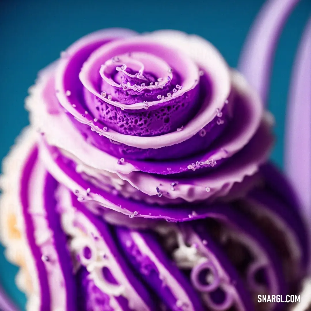 Close up of a cupcake with purple icing on it's top and a spiral design on the bottom. Example of RGB 218,112,214 color.