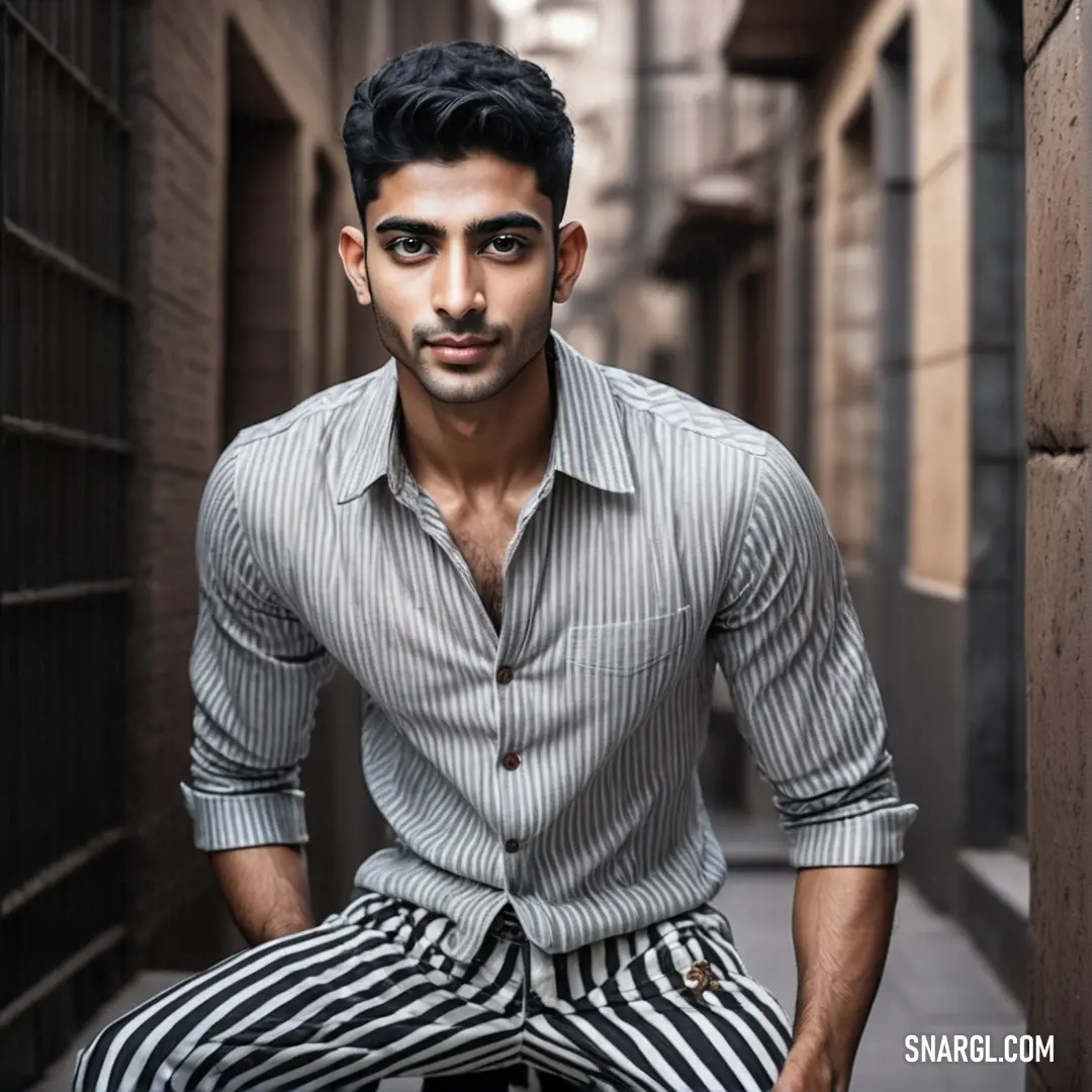 Man on a chair in a narrow alleyway wearing striped pants and a shirt with a button up