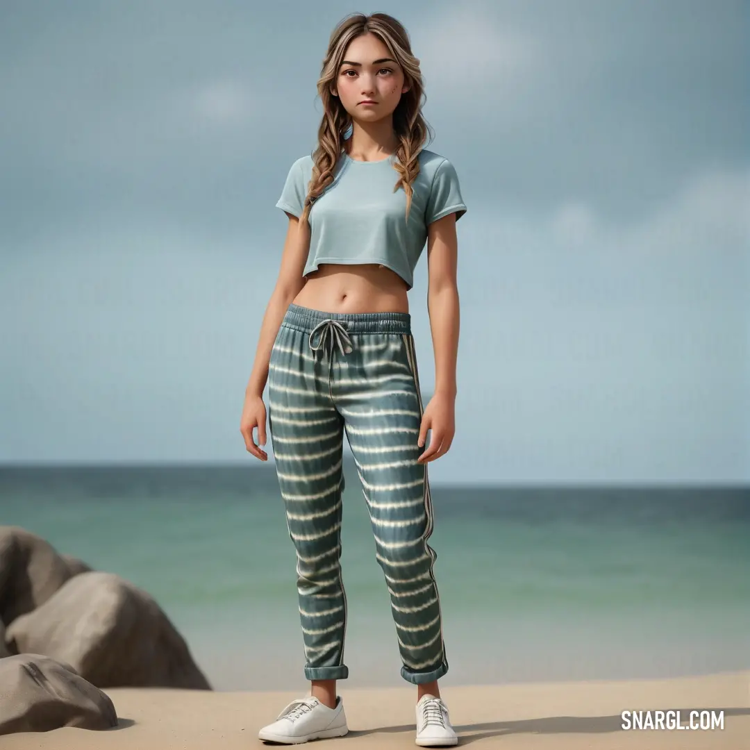 Woman standing on a beach next to the ocean wearing a crop top and striped pants with a tie