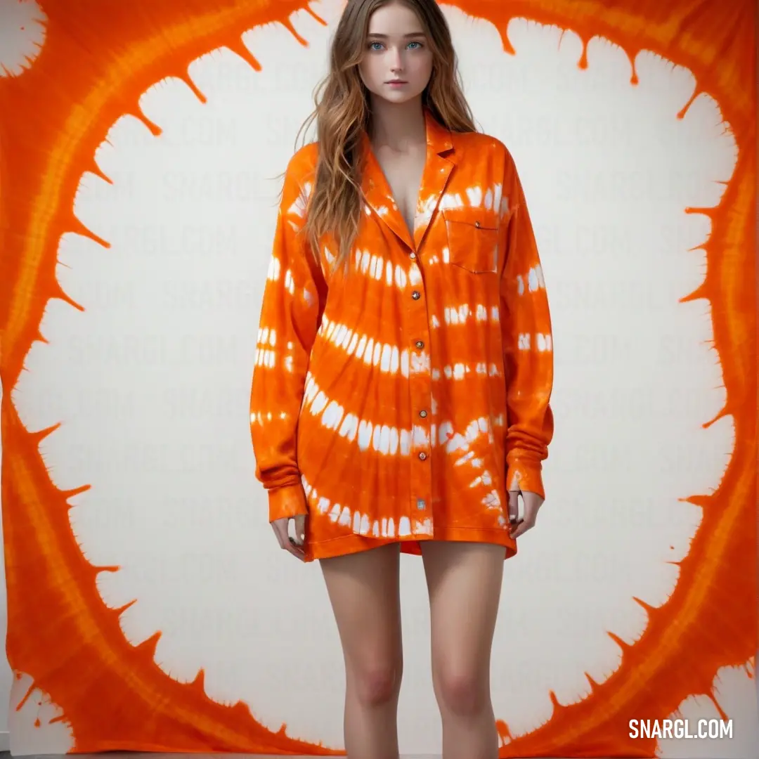 Woman standing in front of a tie dye backdrop wearing an orange shirt dress and white shoes