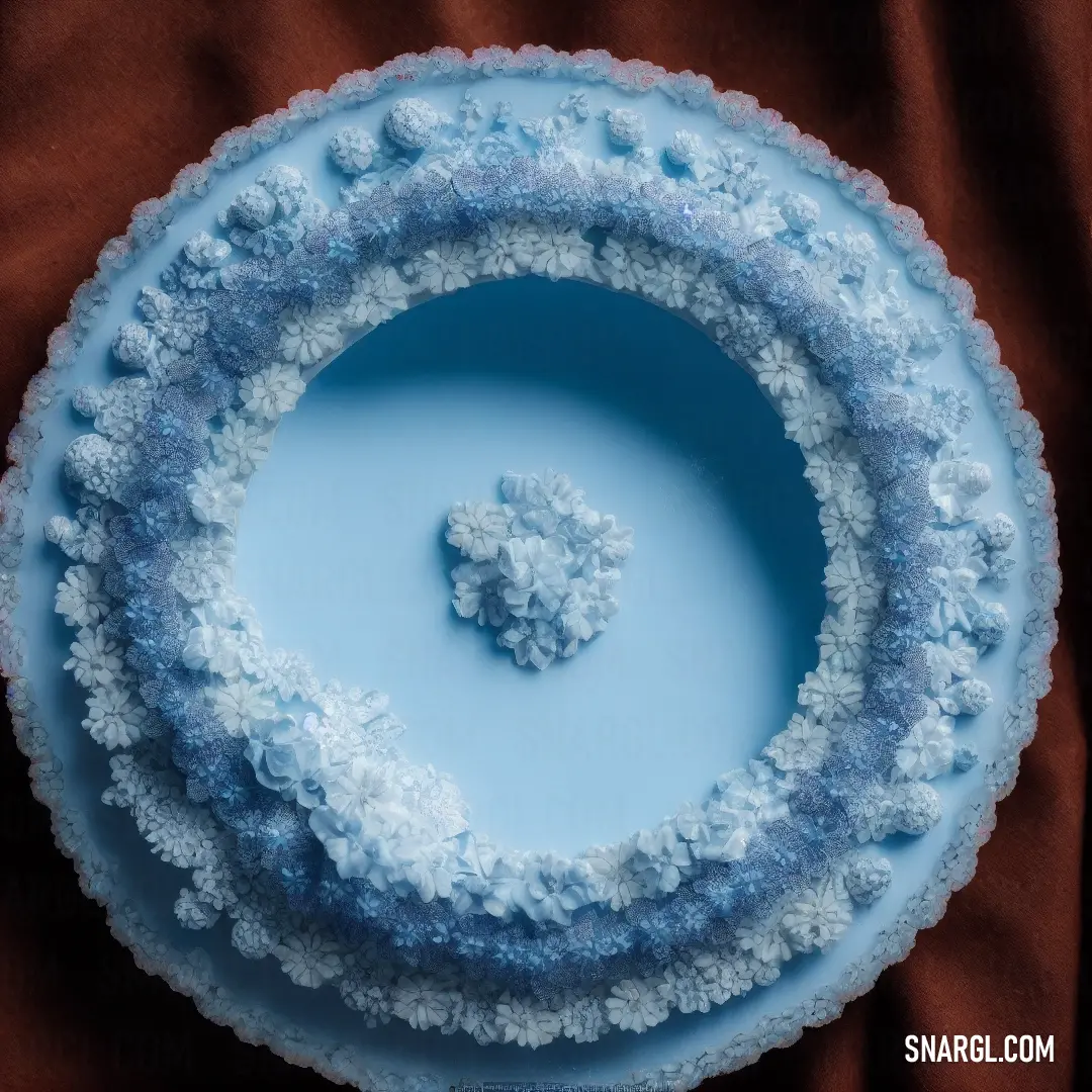 Blue cake with a white frosting design on it's bottom and a piece of a small piece of cake on top