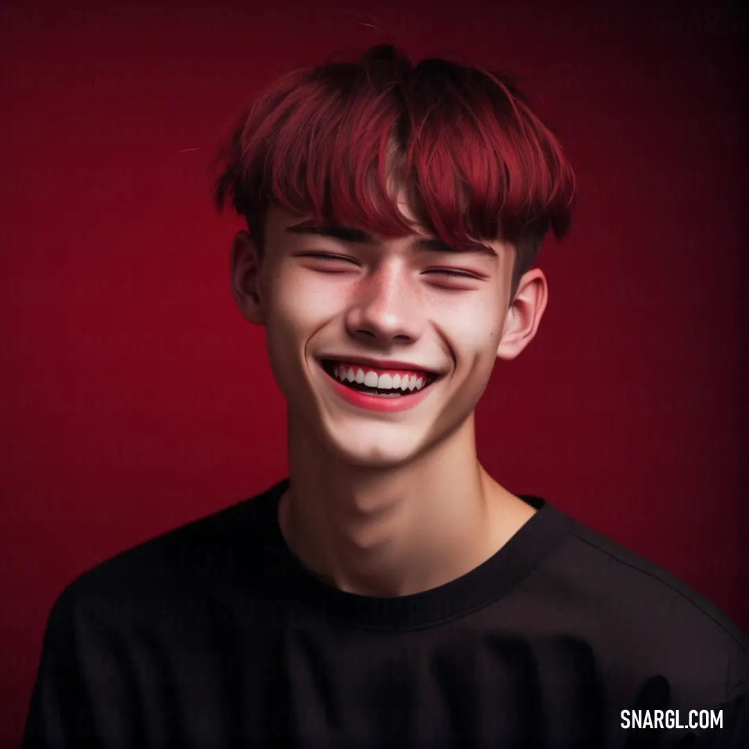 Young man with red hair smiling at the camera with a red background behind him