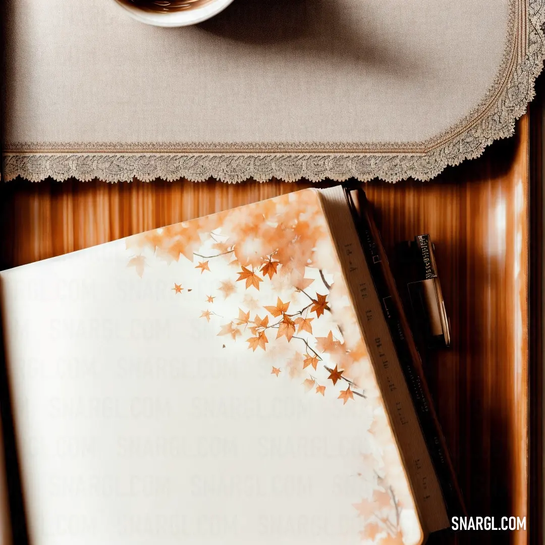 Cup of coffee and a notebook on a table with a pen and pencils on it and a picture of a tree