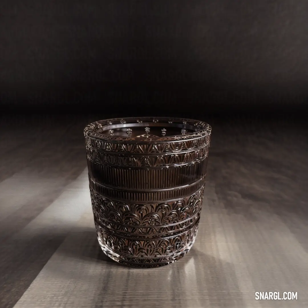 A glass cup sits elegantly on a wooden table, casting a soft shadow against a black background. The simplicity of the cup is contrasted by the warmth of the table's natural grain and the depth of the shadow.