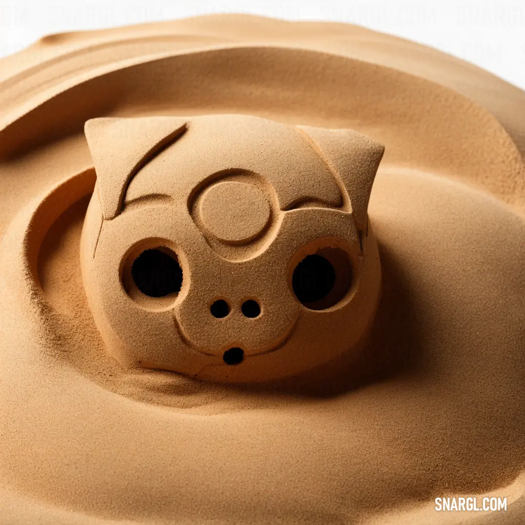 Pale gold color. Clay cat head is shown in the sand of a clay sculpture