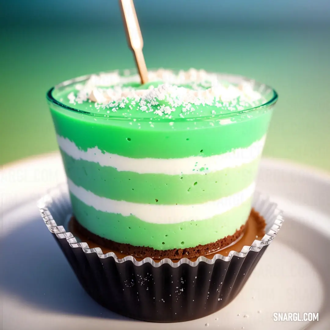 Cupcake with a green frosting and a single candle sticking out of it's top on a plate