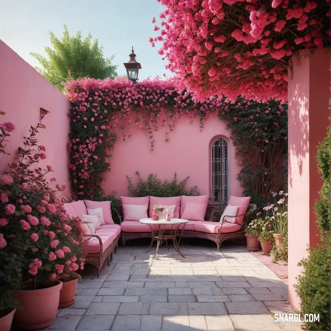 Pink patio with a couch and table surrounded by flowers and plants on the wall. Color #DB7093.