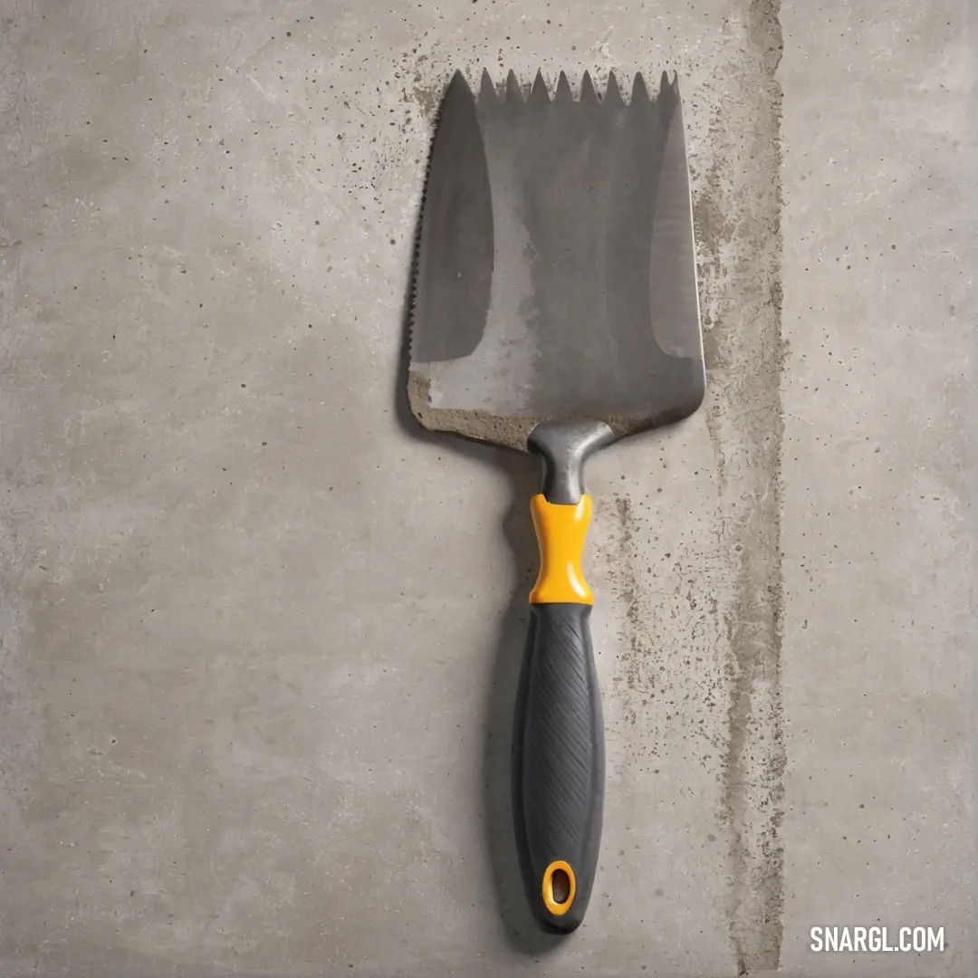 A striking large spatula with a yellow handle resting on a smooth concrete surface, contrasting beautifully with a gray backdrop. Its design and color showcase functionality and style, perfect for the modern kitchen.