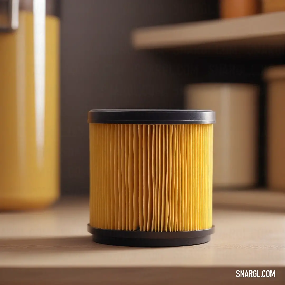 A bright yellow air filter rests atop a wooden table next to a matching yellow canister. The warm, cheerful color of the objects contrasts beautifully with the natural texture of the wood. The combination of yellow tones gives off a sense of freshness and