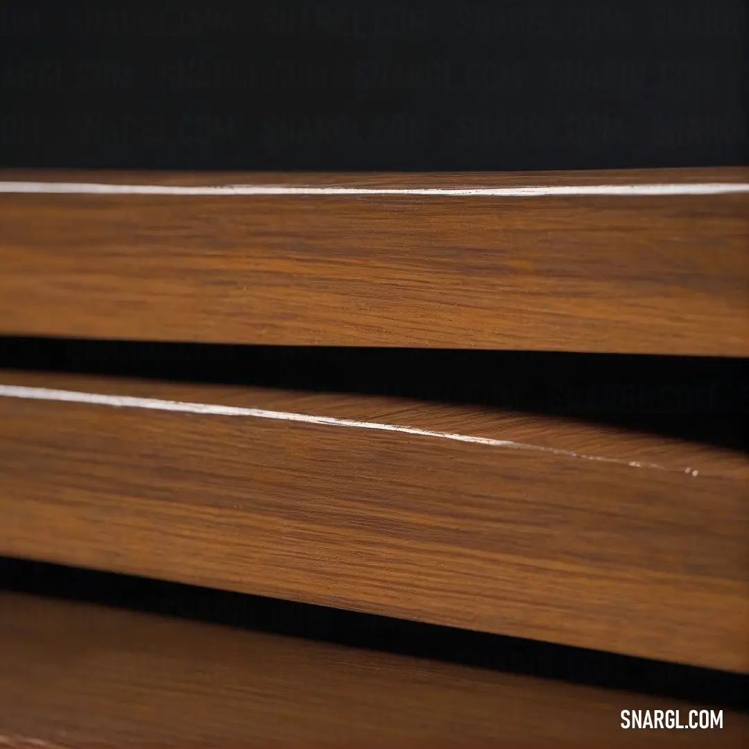 Close-up of a wooden window sill with rich, warm brown tones, contrasting against a dark, almost black background. The subtle texture of the wood and deep shadows create a cozy and intimate atmosphere.