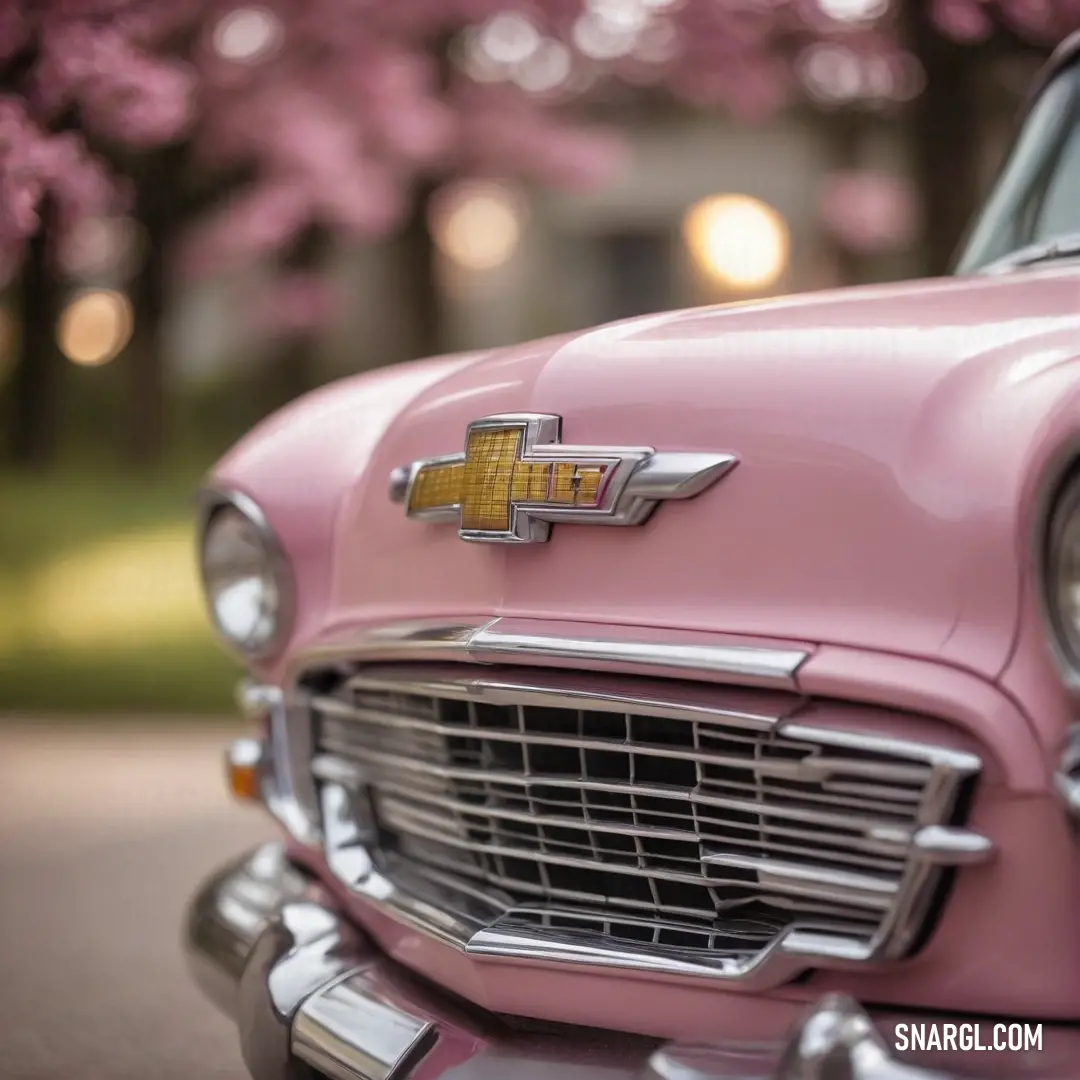 A vibrant pink car glistens under the sunlight, parked gracefully beside a roadside, with delicate pink flowers flourishing in the background, creating a serene and picturesque scene. The car embodies elegance, harmonizing perfectly with the colorful bloo