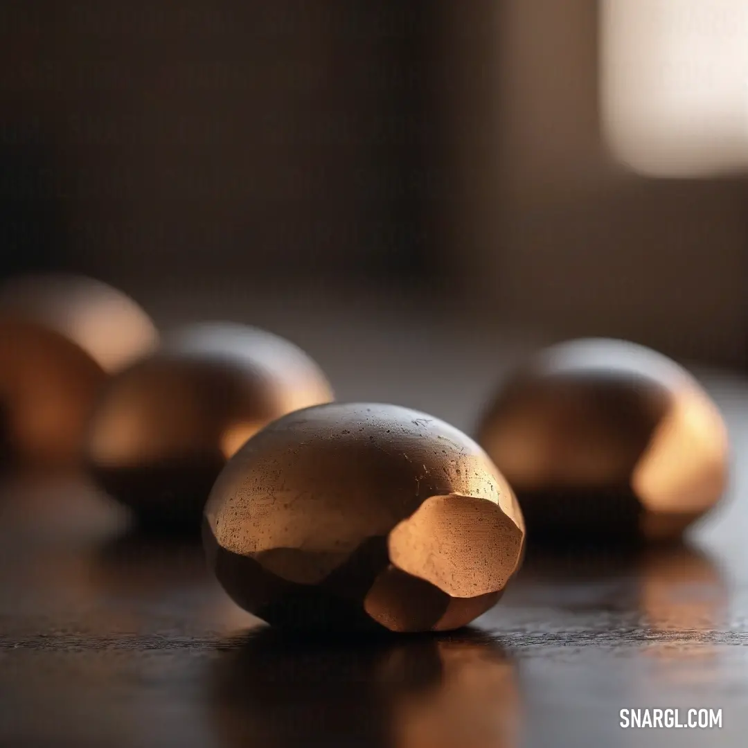 A cluster of metal balls rests side by side on a table, reflecting the soft light of a nearby window. The scene is filled with a warm amber-orange color, creating a calm yet dynamic mood that draws attention to the intricate details of the objects.