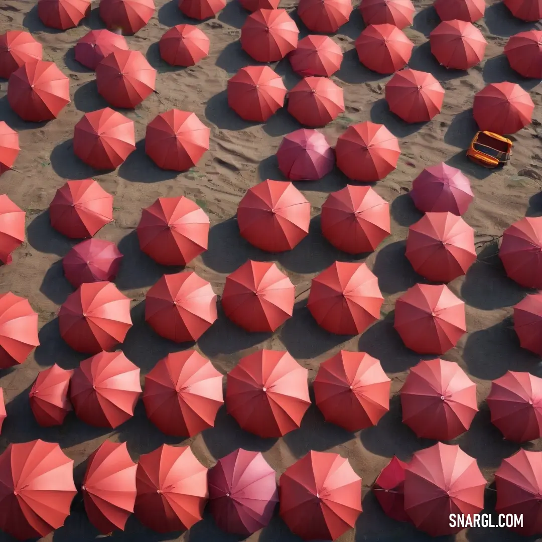 A vibrant collection of red umbrellas lies scattered across a golden sandy beach, next to a bright yellow bench. The sea in the background and the sun-soaked scene create a lively, inviting atmosphere perfect for a summer day.