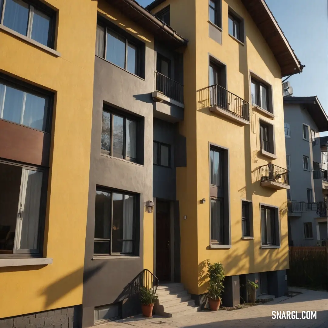 An eye-catching yellow and gray building featuring an elegant staircase leading to a second story adorned with charming balconies. The blend of these colors and architectural elements creates a welcoming atmosphere, perfect for both residents and visitors