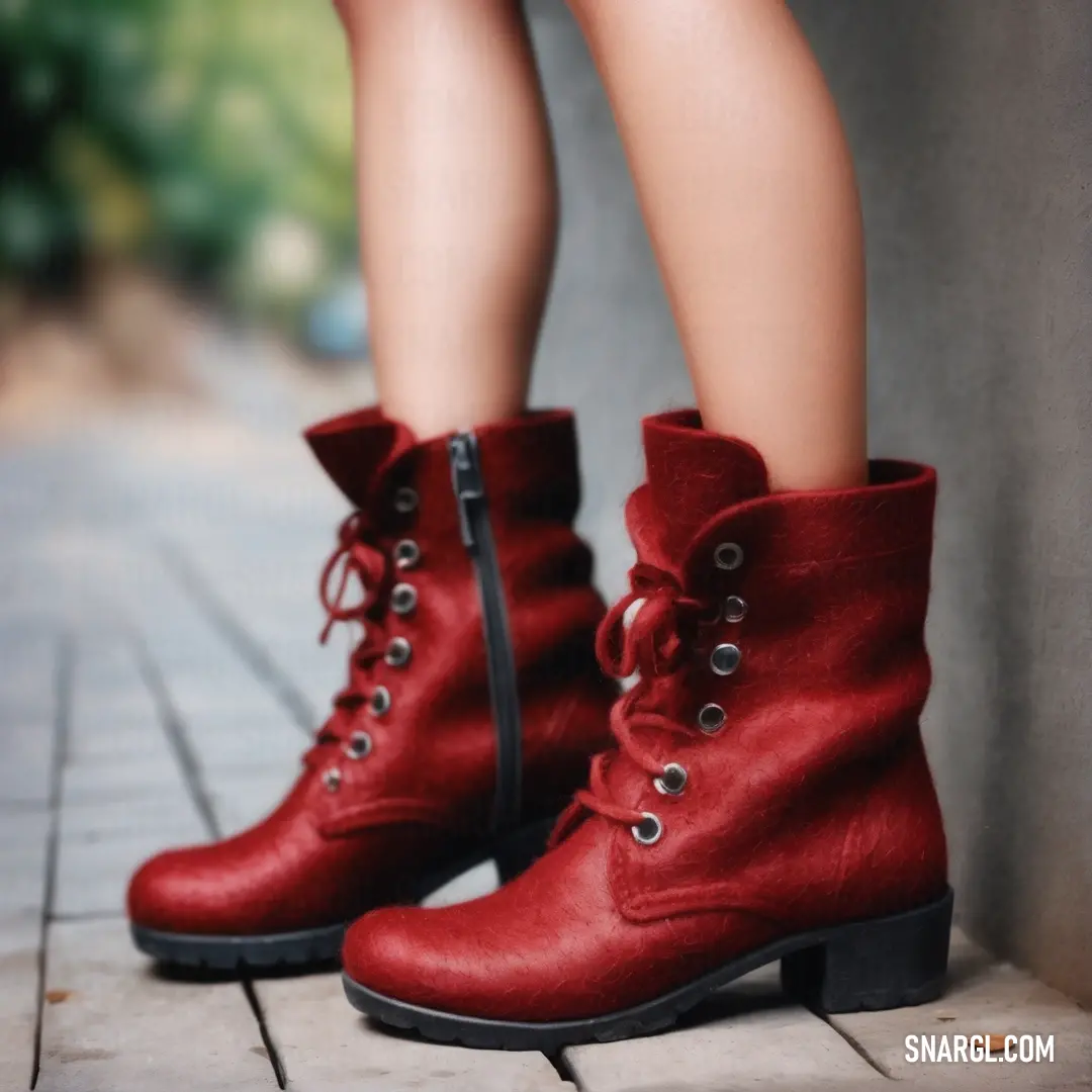 A stylish view of a woman's legs clad in red boots, poised on a textured brick floor, with a brick wall in the background, showcasing a vibrant urban aesthetic that captivates the eye.