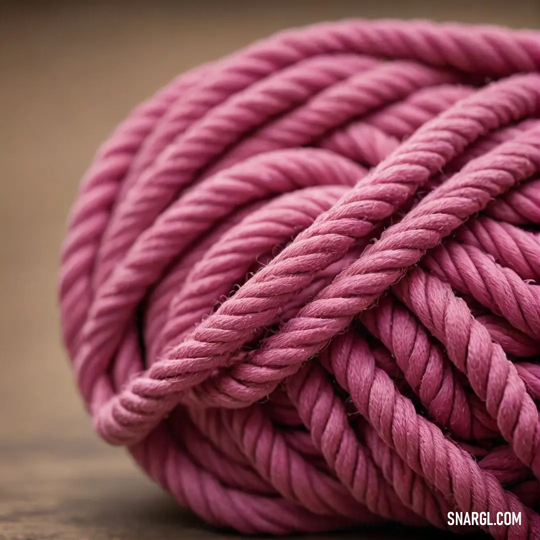 A close-up of a pink rope artfully placed on a rustic wooden surface, set against a dark backdrop, portraying a harmonious juxtaposition of textures and colors that captures attention.