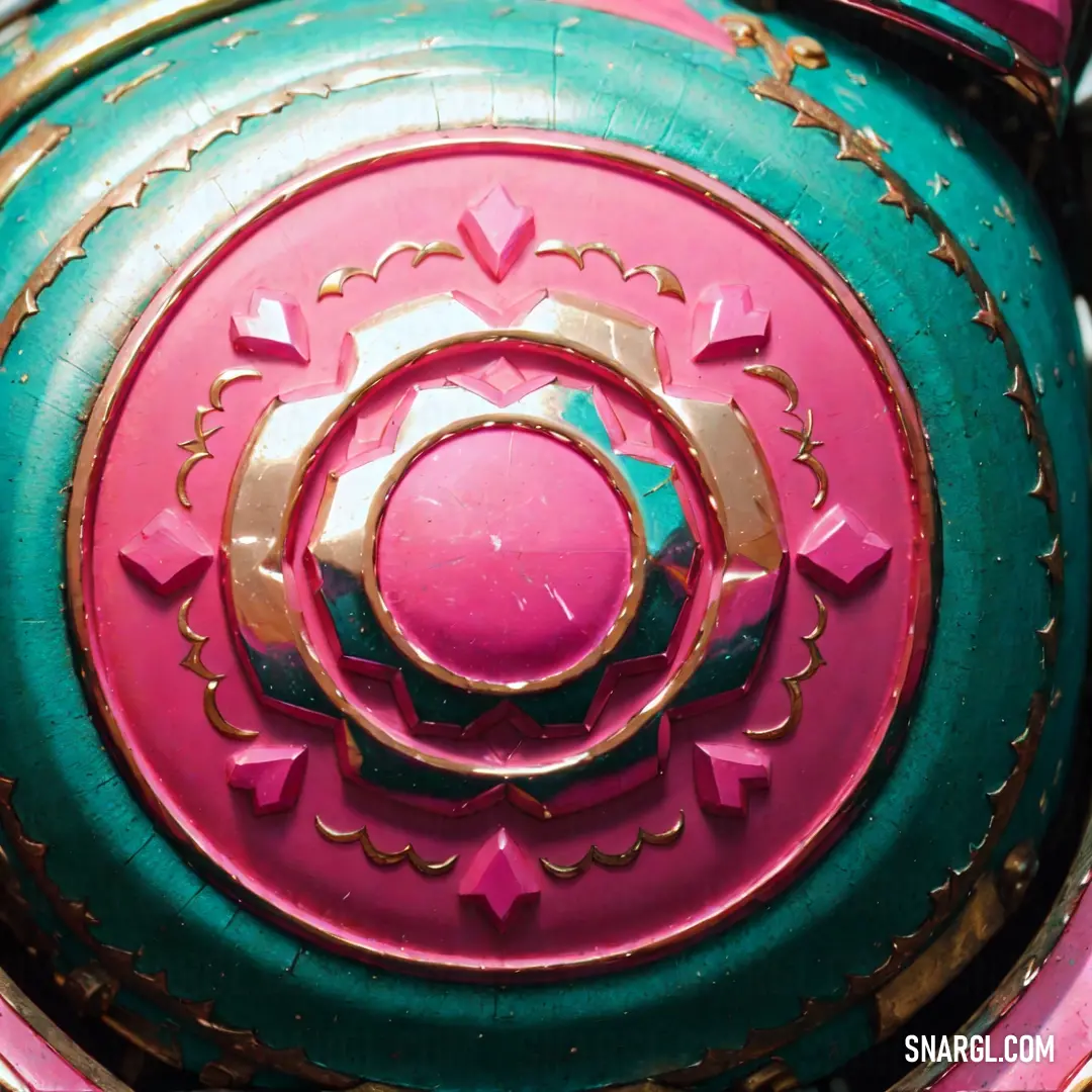 Close up of a pink and green object with gold accents and a circular design on the center of the object