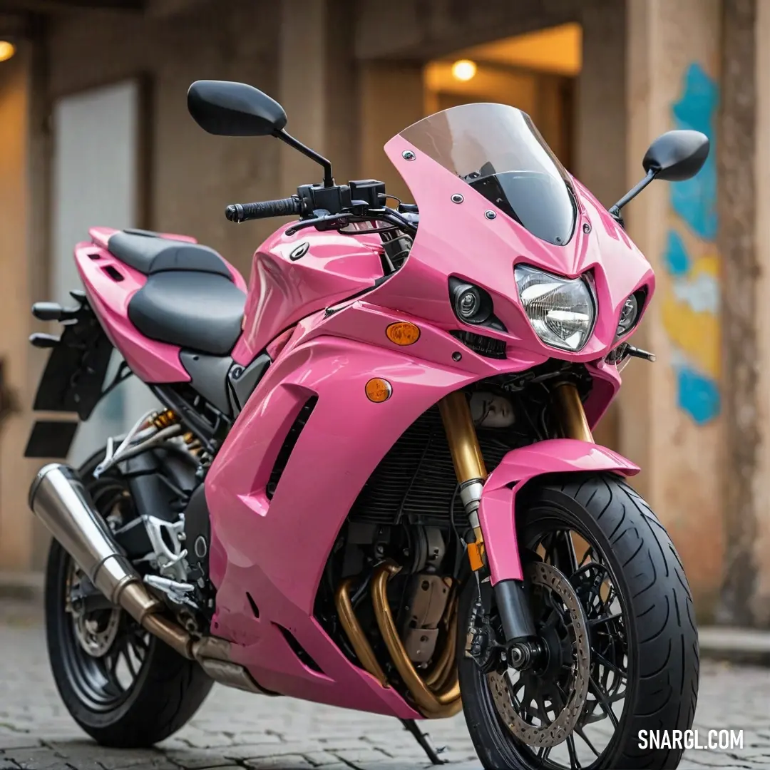 A pink motorcycle stands parked on a brick road, its bold color contrasting with the urban backdrop of graffiti-covered walls. The vibrant PANTONE 2060 pink pops against the raw textures of the city street.