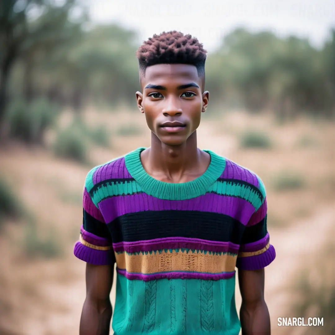 PANTONE 2077 color. Man with a short haircut and a sweater on standing in a dirt road in a field with trees