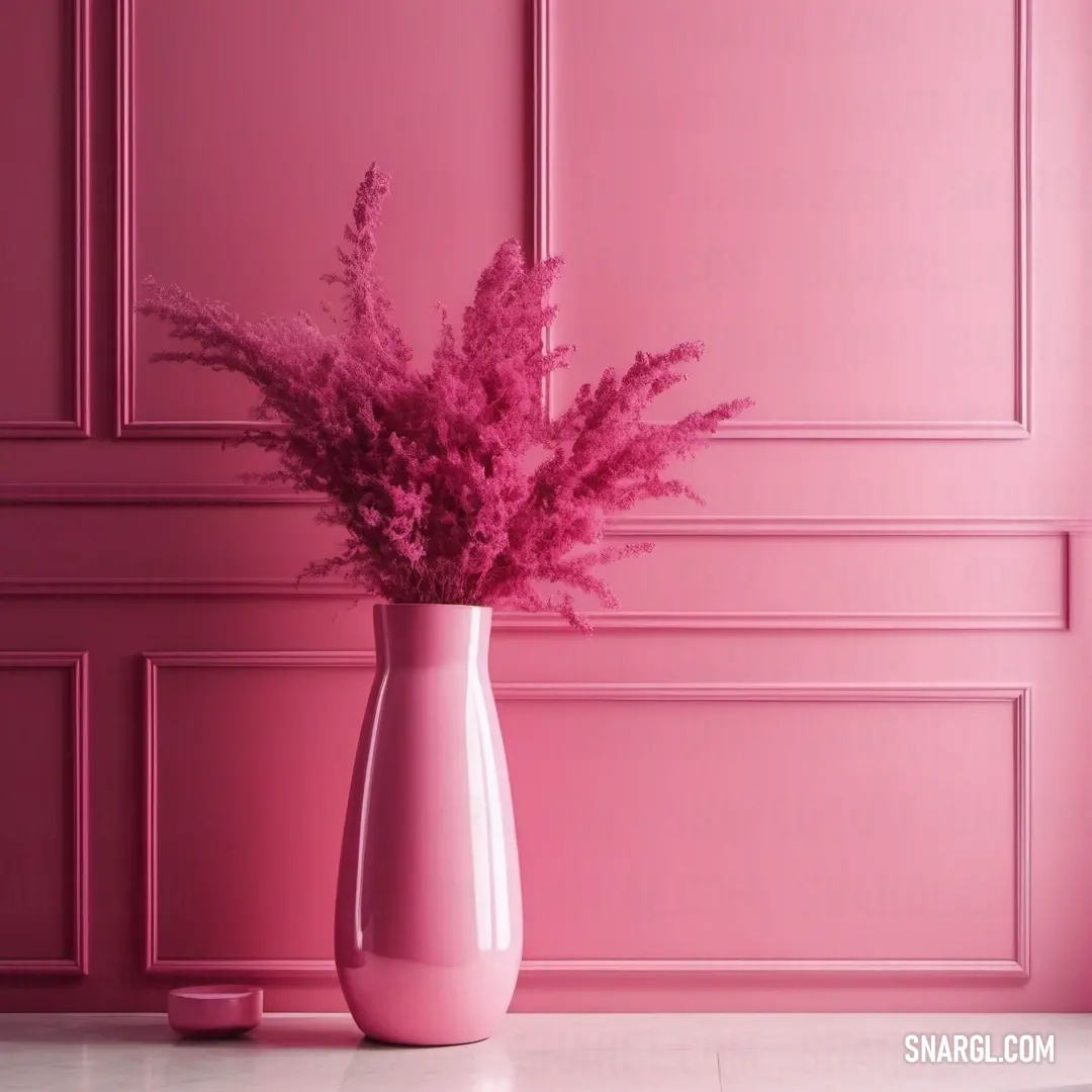 A pink vase filled with soft pink flowers sits on a table in front of a matching pink wall, creating a monochromatic yet refreshing aesthetic. The vibrant color of PANTONE 214 fills the scene with warmth and beauty.