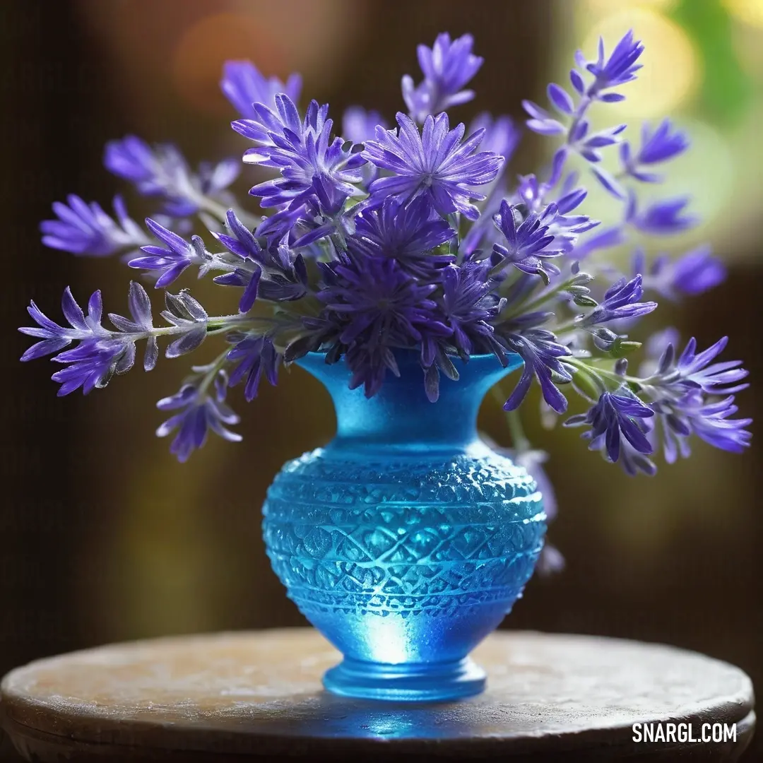 PANTONE 2171 color example: Blue vase with purple flowers in it on a table top with a blurry background