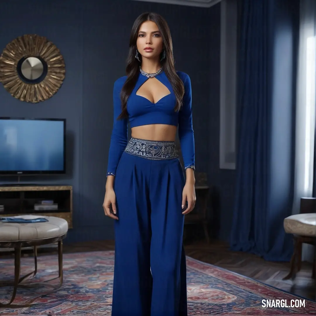 A woman stands confidently in a room, wearing a stylish blue outfit. The soft blue color of her attire contrasts beautifully with the room’s décor, which includes a rug, a mirror, and a television mounted on the wall.