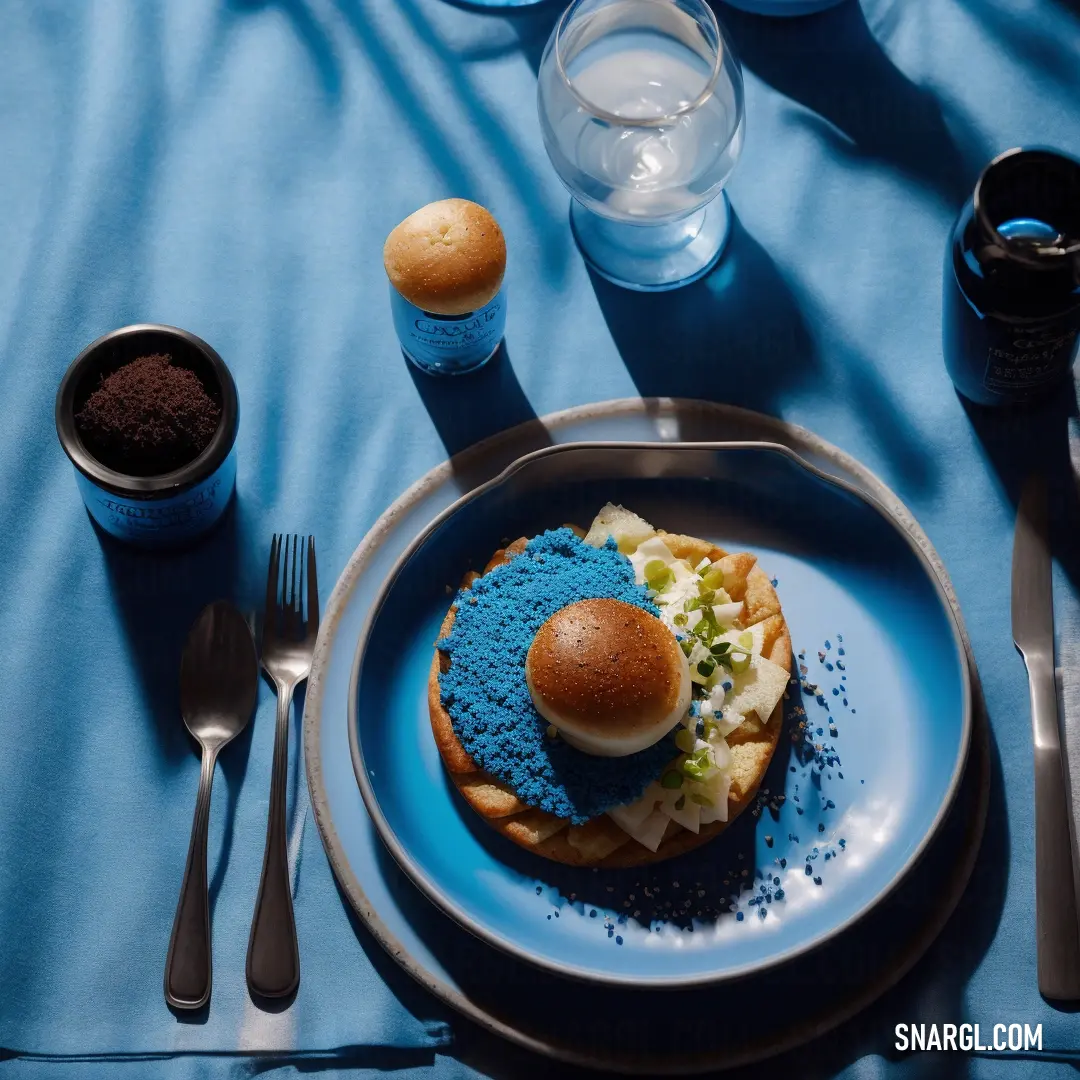 Blue plate with a sandwich and some drinks on it and a spoon and fork on the side of the plate. Color CMYK 92,24,0,0.
