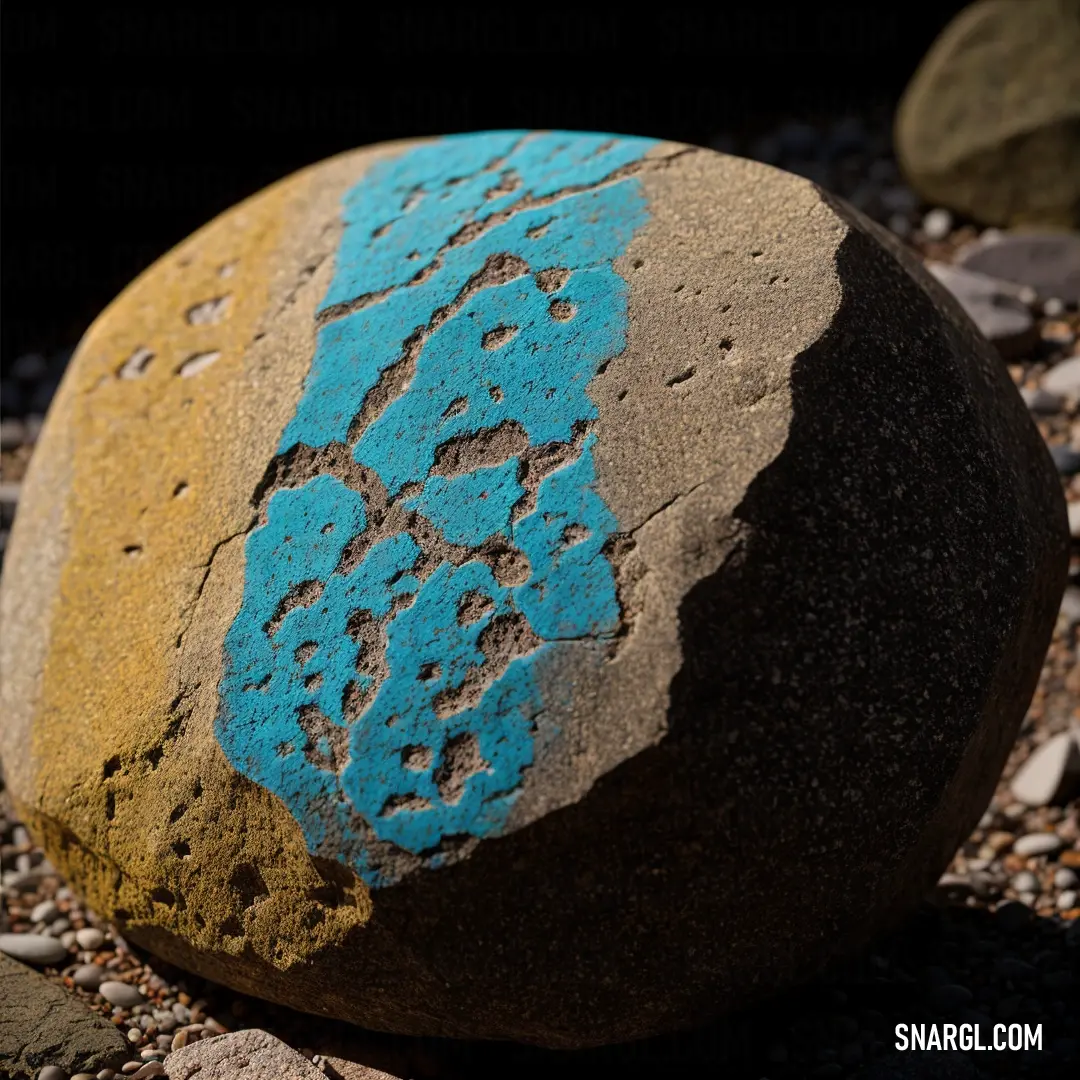 Rock with a blue design on it on a rocky ground with gravel and rocks around it and a black background. Example of RGB 0,138,176 color.