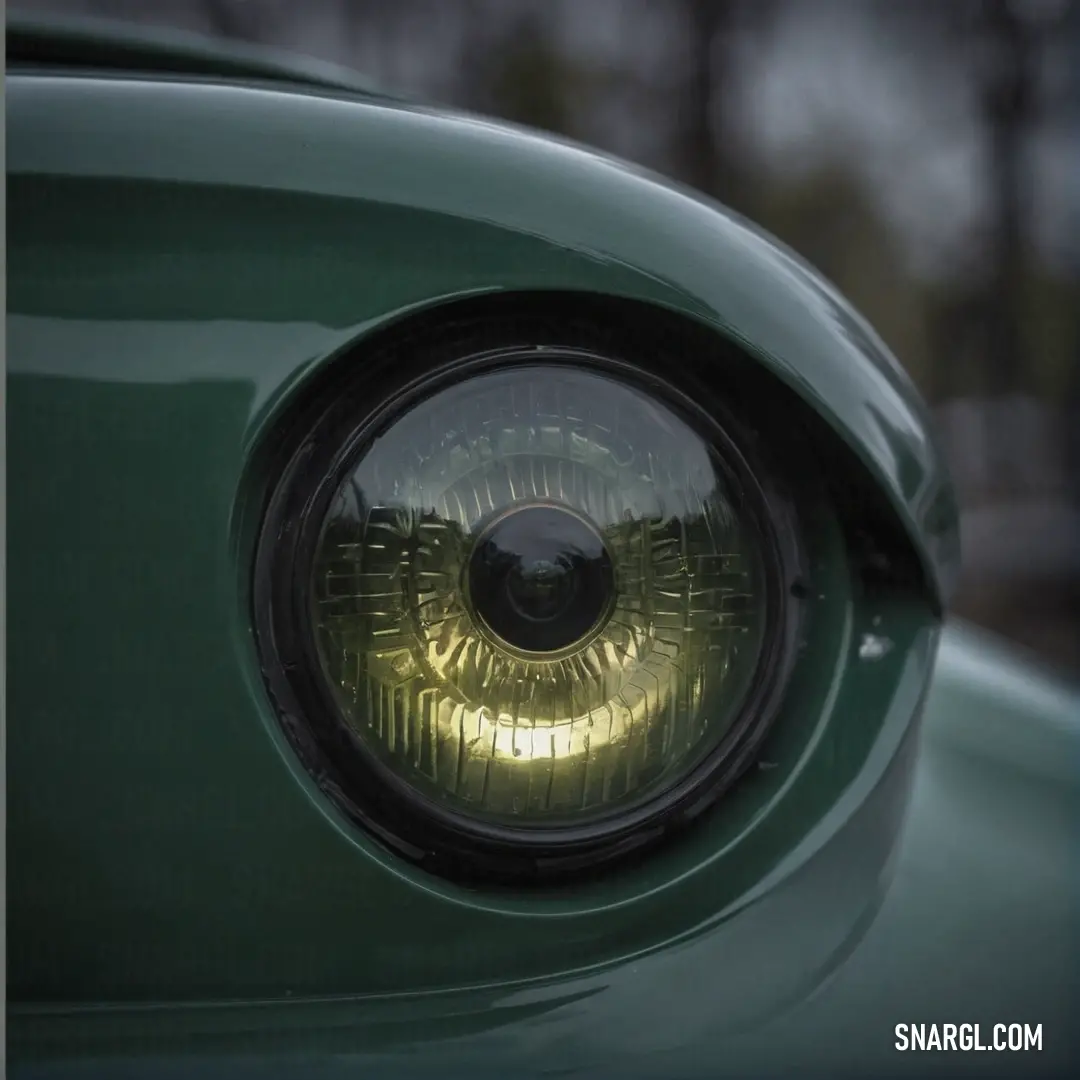 A magnificent close-up of a green car casually parked, adorned with a yellow headlight glow and framed by the presence of a nearby tree; the allure of PANTONE 2328 color captures the eye.