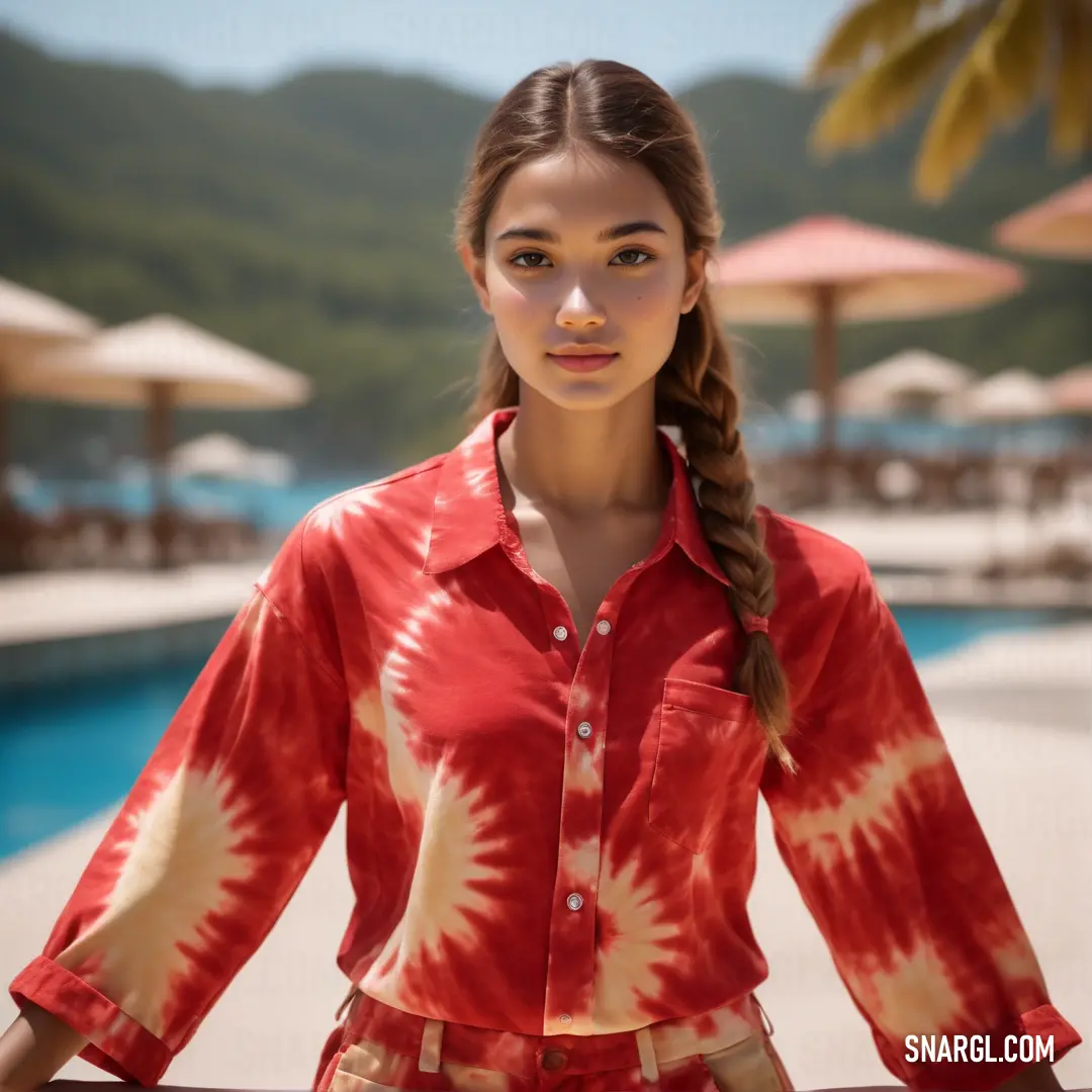 Woman standing in front of a pool with a red shirt on and a braid in her hair. Example of CMYK 0,95,100,21 color.