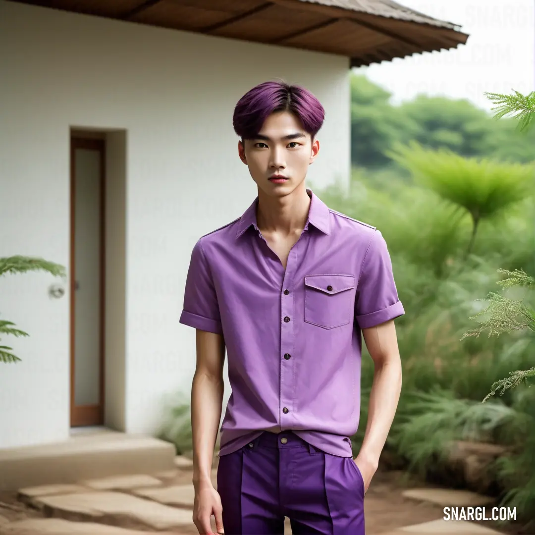 Man with a purple shirt and purple pants standing in front of a house with a green bush in the background. Example of #762162 color.