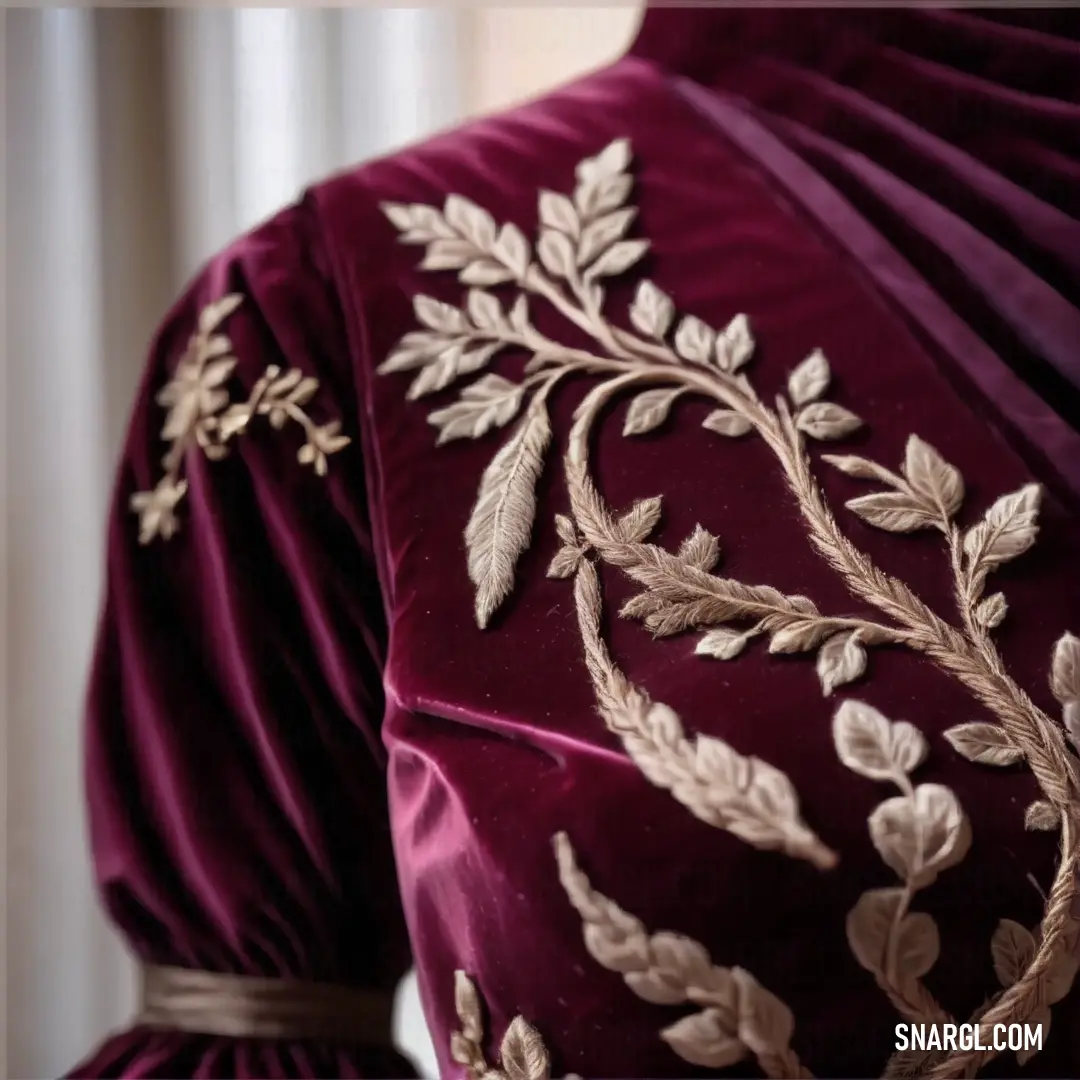 Close up of a dress with a gold leaf design on it's back and a purple velvet dress with a gold leaf design on it