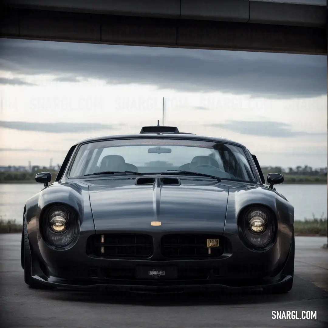 Car parked in a parking garage next to a body of water with a cloudy sky in the background. Color #596676.