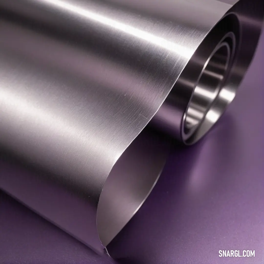 A roll of metal gleams softly on a fresh purple surface, combining texture and color in an alluring display that highlights the beauty of industrial design and nature's artistry in harmony.