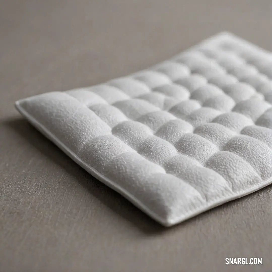 An intimate close-up showcasing a plush mattress adorned with a soft white pillow, while a stylish black and white clock elegantly hangs on the wall, making this setup inviting and cozy for a restful retreat.