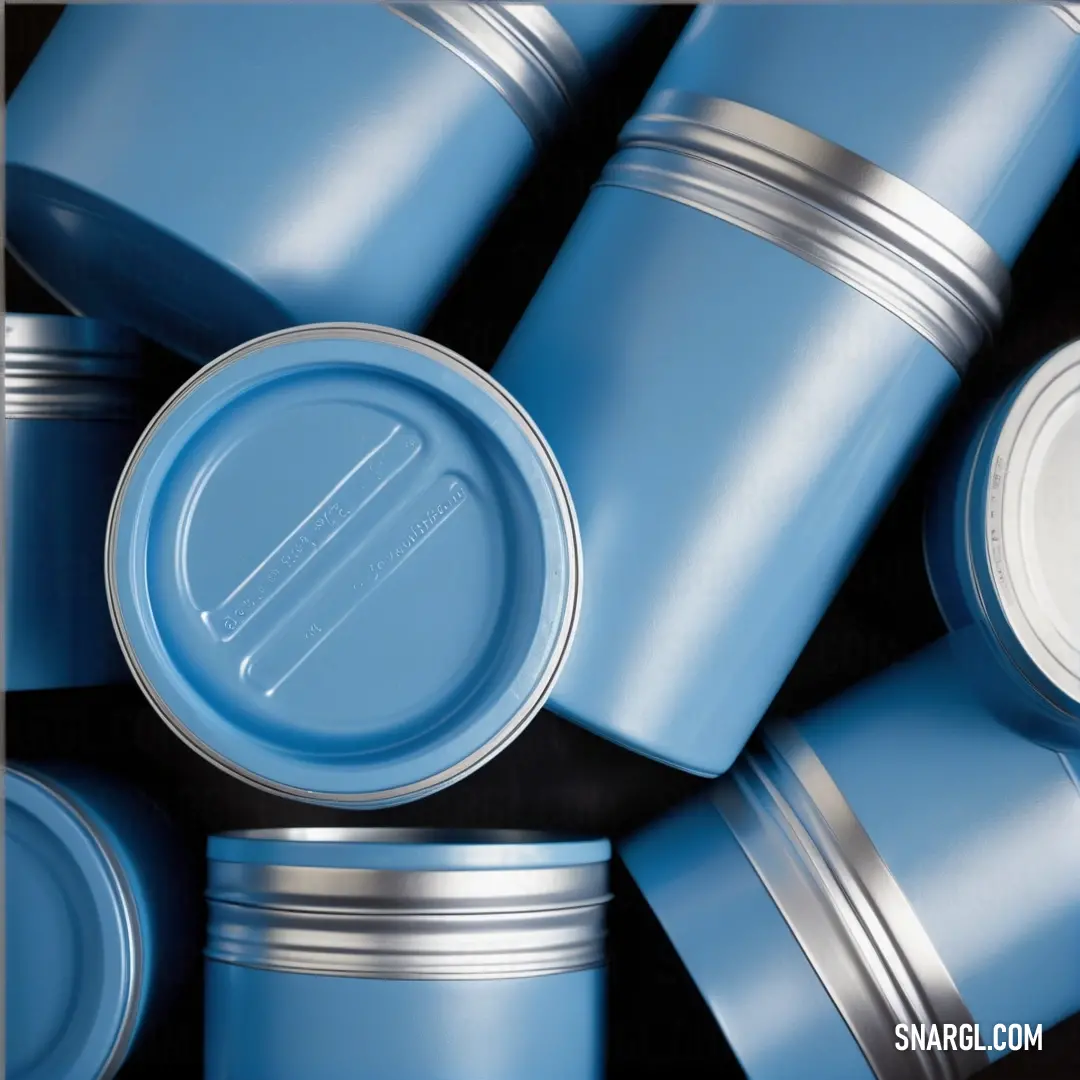 A stack of blue cans with lids resting on top of one another, their white bottoms creating a contrast against the rich blue tones. The simplicity of the arrangement offers a clean, minimalist aesthetic.