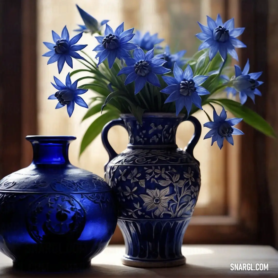 Blue vase with flowers in it next to a blue vase with flowers in it on a table. Color PANTONE 2748.