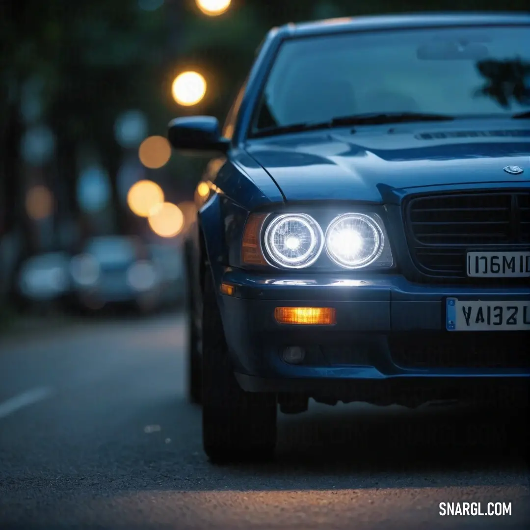 A stunning blue car sits parked under the night sky, its headlights illuminating the street with a warm glow. The rich color and striking presence add a touch of luxury and elegance to the urban environment.