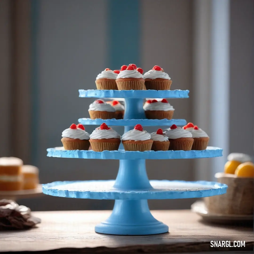 A PANTONE 293 blue cake stand holds a delicate arrangement of cupcakes, each topped with a lemon slice. The vibrant color of the stand perfectly complements the sweetness of the display.