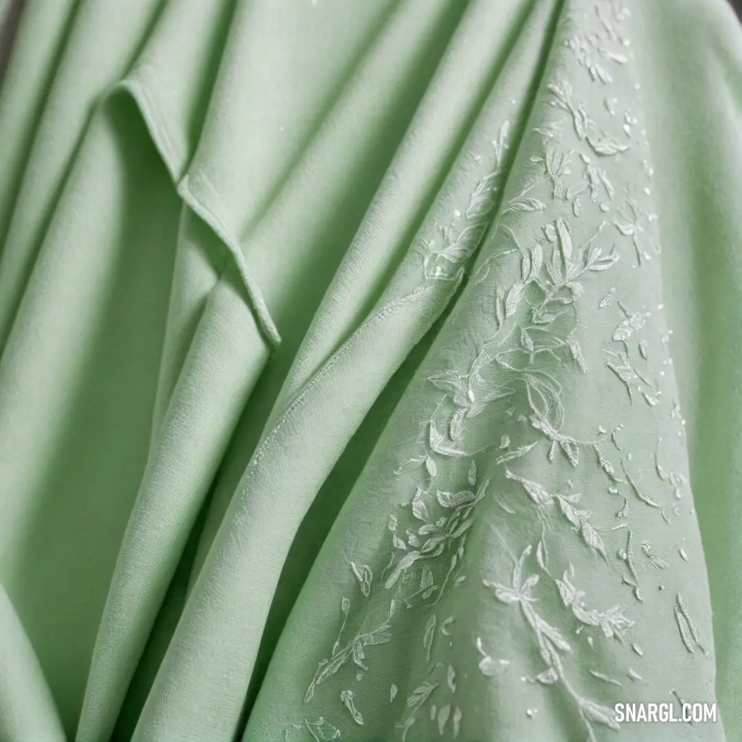 A vibrant green dress adorned with delicate white flowers cascades elegantly, highlighted by a lace trim at the hem. The fresh greenery and floral accents dance harmoniously, embodying joy and celebration within the PANTONE 2965 palette.