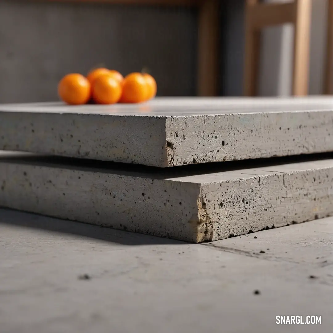 A couple of cement slabs sit atop a table beside fresh oranges. A chair can be seen in the background, while the cool blue shade of color #20344B brings a modern touch to the scene.