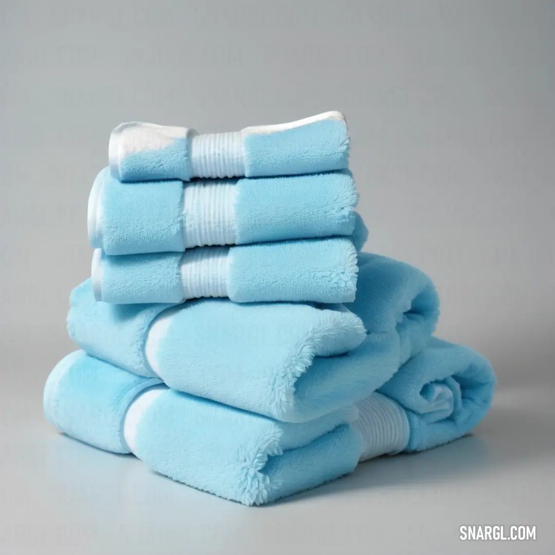 A neatly stacked pile of blue towels rests atop one another on a table. The soft, pastel blue tones of the towels stand out beautifully against the muted gray background, creating a calm and organized aesthetic.