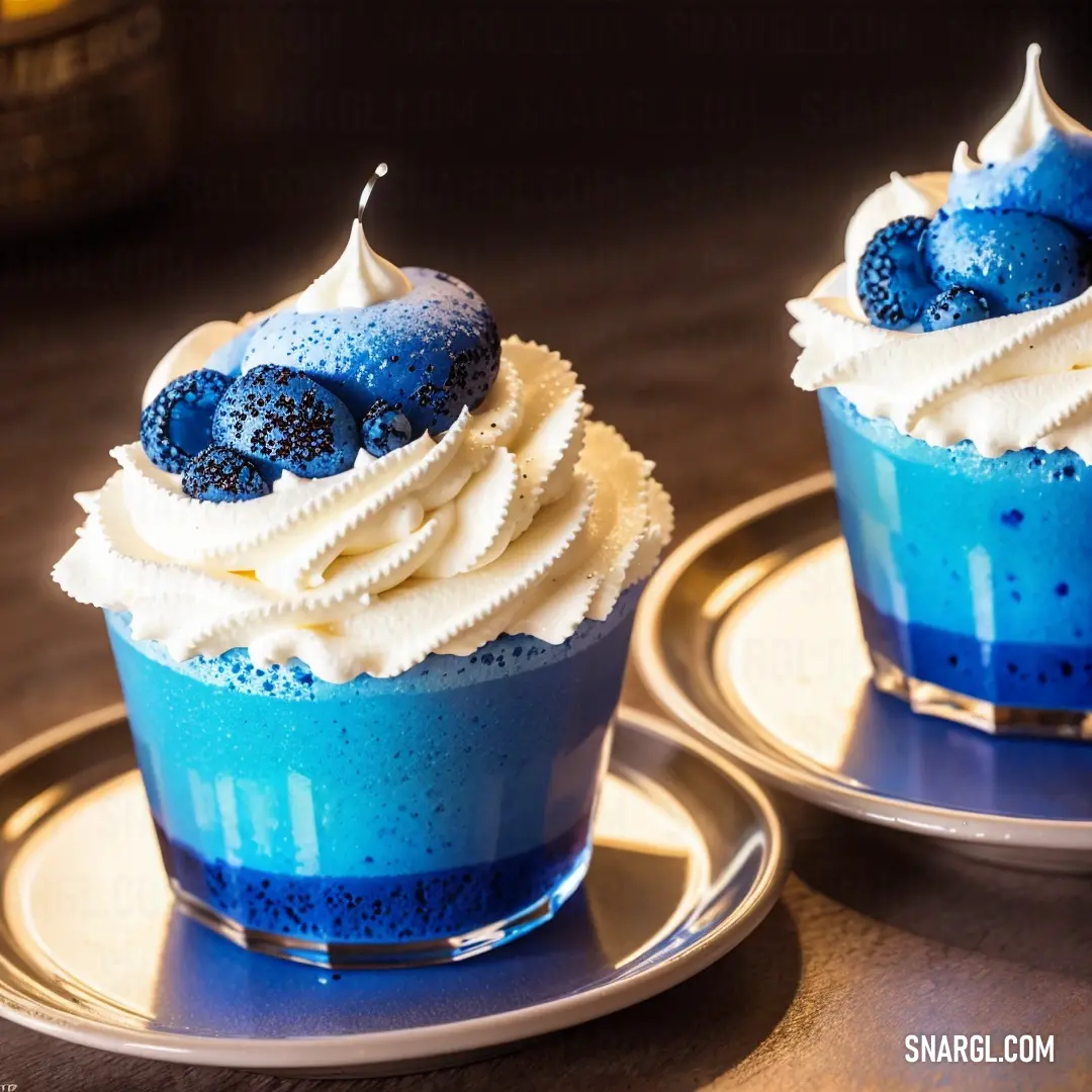 Two blue desserts with white frosting on a plate on a table with a bottle of wine in the background. Color #00B3DB.