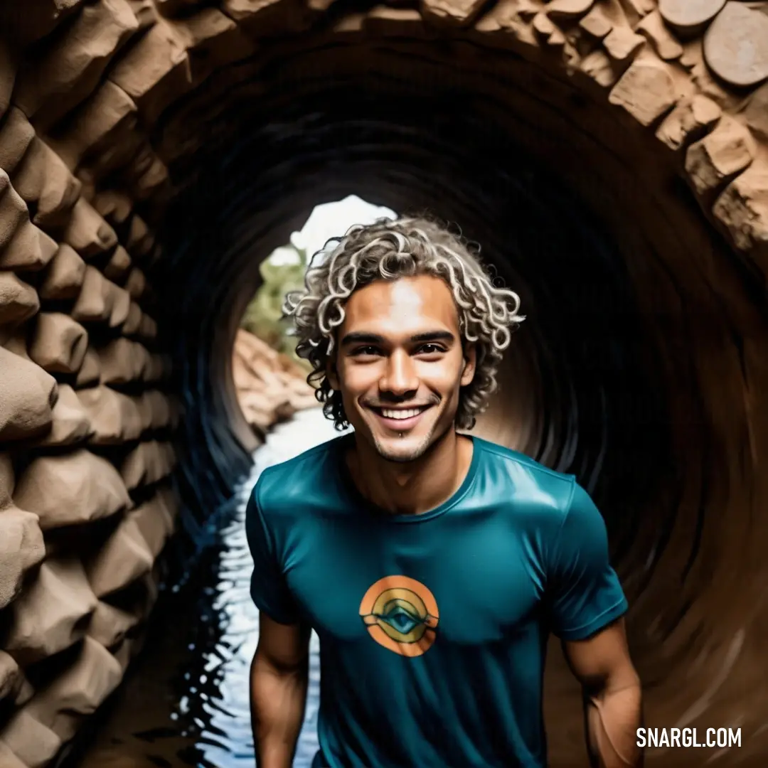 Man standing in a tunnel with a smile on his face and long hair on his head and a green shirt on. Example of PANTONE 316 color.