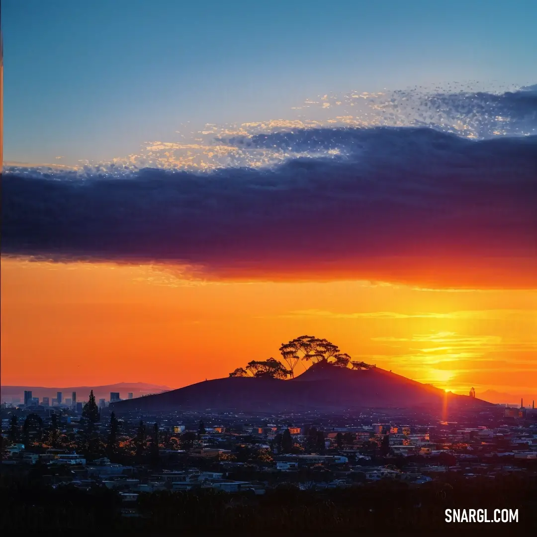 A breathtaking sunset paints the sky over a bustling city, with the silhouette of a towering mountain in the distance. The rich tones of deep green and golden hues blend beautifully, casting a peaceful glow across the landscape.