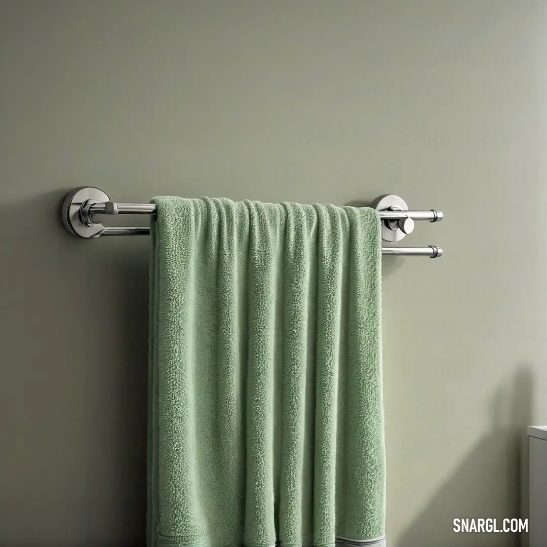 A towel rack with a soft green towel draped over it, positioned beside a window that lets in natural light, illuminating the calm tones of the PANTONE 3435 color. The simple design emphasizes tranquility and functionality in a bathroom setting.