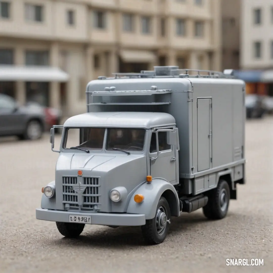 A bright red toy truck sits parked in a lively parking lot, with a modern building serving as its backdrop. The scene radiates a sense of nostalgia and fun, inviting curiosity from passersby.